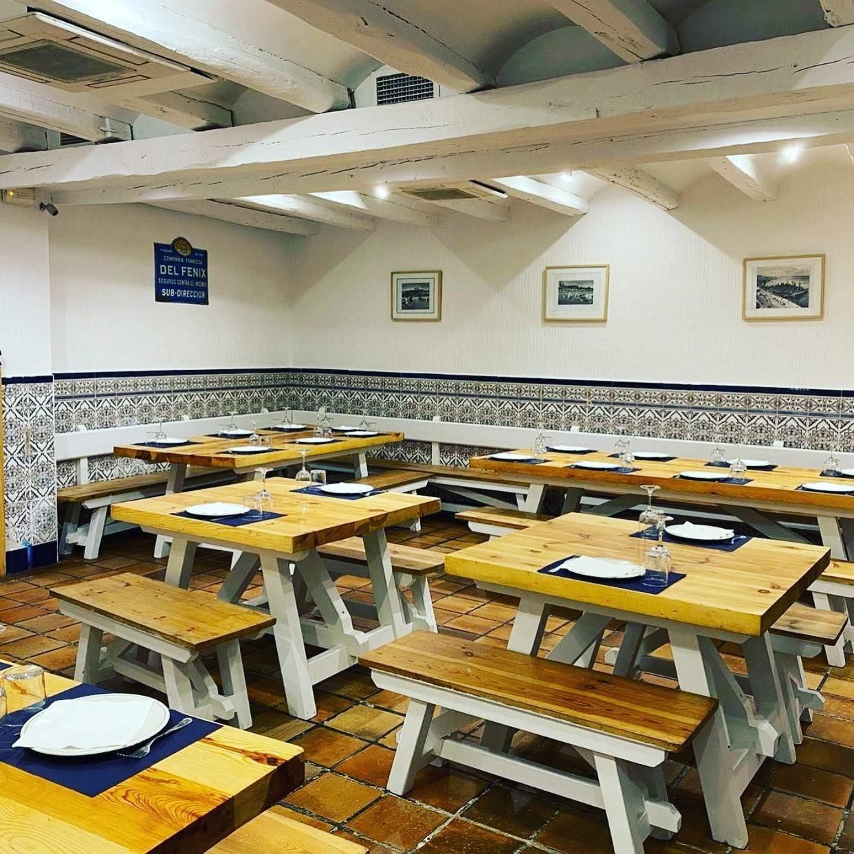 Comedor de Valladolid con mesas y bancos de madera y cenefa de azulejos